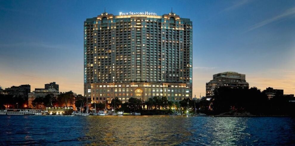 Night view of the Four Seasons Hotel Nile Plaza facade on the Nile banks, highlighting luxury hotel booking services by White Sky Travel.