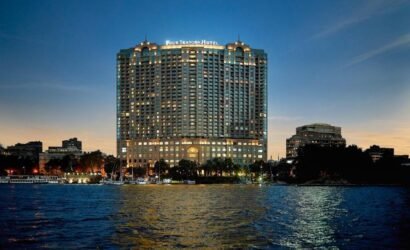 Night view of the Four Seasons Hotel Nile Plaza facade on the Nile banks, highlighting luxury hotel booking services by White Sky Travel.