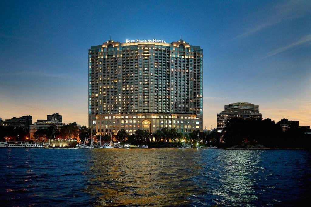 Night view of the Four Seasons Hotel Nile Plaza facade on the Nile banks, highlighting luxury hotel booking services by White Sky Travel.