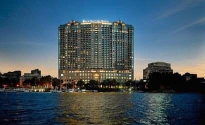 Night view of the Four Seasons Hotel Nile Plaza facade on the Nile banks, highlighting luxury hotel booking services by White Sky Travel.